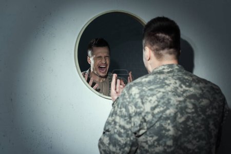 Foto de Veterano militar enojado gritando cerca del espejo mientras sufre trastorno de estrés postraumático - Imagen libre de derechos