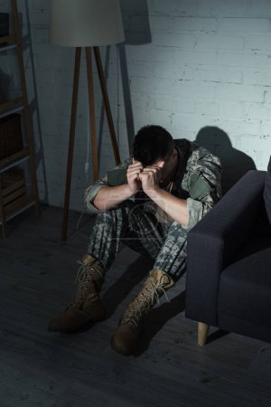 Soldier in uniform suffering from dissociation disorder at home at night 