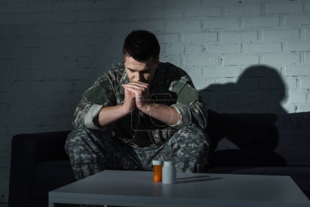 Military man with mental dissociation sitting near pills at home at night 