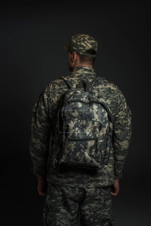 Rückseite patriotischer Soldat in Tarnuniform, stehend mit Rucksack isoliert auf grau 