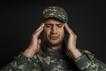 patriotic soldier in camouflage uniform and cap suffering from ptsd isolated on black 