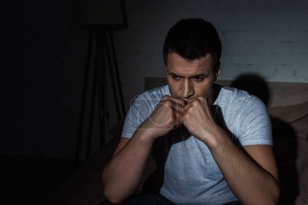Photo for Depressed man in white t-shirt sitting on bed while struggling from ptsd - Royalty Free Image