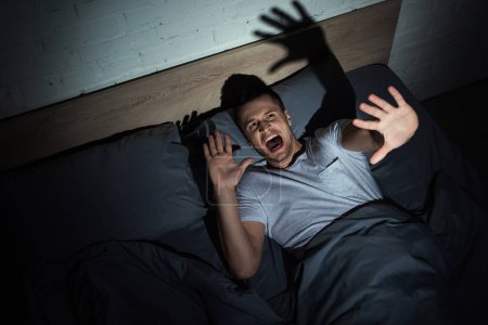 top view of man having anxiety and screaming while having nightmares at night 