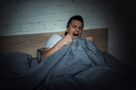 Téléchargez les photos : Homme effrayé avec des attaques de panique crier tout en faisant un cauchemar la nuit - en image libre de droit