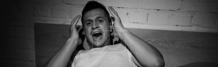 foto monocromática del hombre estresado con ataques de pánico gritando por la noche, pancarta 