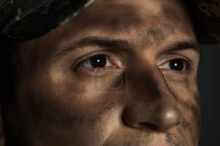 close up view of eyes of military man with dirt on face suffering from ptsd isolated on grey 