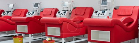 row of comfortable medical chairs with ergonomic design, trash buckets and automated transfusion machines with monitors in modern blood donation center, banner
