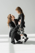 modern mother and daughter, businesswoman in suit hugging schoolgirl in uniform with plaid skirt, blazers, getting ready for new school year, encouraging, looking at each other puzzle #659557642