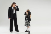 stylish mother and child wearing sunglasses, happy businesswoman in formal attire looking at schoolgirl in uniform on grey background in studio, fashionable family, modern parenting  Longsleeve T-shirt #659557852