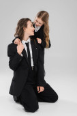 happy schoolgirl hugging working mother, cheerful girl in school uniform looking at mom in suit on grey background, formal attire, fashionable family, bonding, modern parenting  Mouse Pad 659557956