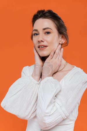 Photo for Summer trends, sensual young woman in white sun dress looking at camera and touching face on orange background, stylish posing, lady in white, fashion model, vibrant background, portrait - Royalty Free Image