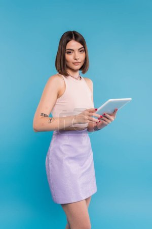 brunette young woman with short hair, tattoos and nose piercing digital tablet laptop on blue background, generation z, summer trends, attractive, social media influencers, tablet user 
