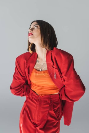 lady in red, young brunette woman with short hair posing in suit on grey background, generation z, trendy outfit, fashionable model, professional attire, executive style 