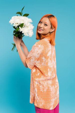 floral bouquet, spring vibes, joyful and young asian woman with dyed hair holding white flowers on blue background, casual attire, generation z, happy face, youth culture, beautiful and trendy 