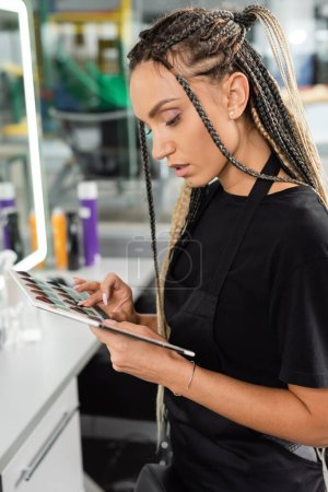 Photo for Hair professional, hairstylist with braids choosing color while holding hair color palette in beauty salon, hair extension, beauty worker, salon job, beauty salon work, hair trends - Royalty Free Image