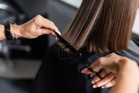 Photo for Close up of hairdresser cutting short brunette hair of female client, beauty worker, haircut, salon job, beauty industry, scissors and professional comb, salon hair tools, cropped view - Royalty Free Image