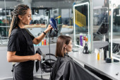 salon blow dry, hairdresser with round brush and professional hair dryer styling hair of female customer, brunette woman with short hair, beauty salon, hair volume, blowout  Poster #660917080
