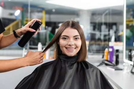 salon services, hair spray, hairdresser styling hair of female customer with nose piercing, happy brunette woman with short hair, beauty salon, hair volume, hair professional, hairdressing cape 
