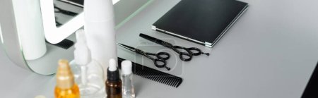 Photo for Hairstyling products, hairdressing scissors, bottles, hair oil, comb, hair palette book near mirror in beauty salon, hair essentials, beauty industry, hair fashion, hair industry, banner - Royalty Free Image