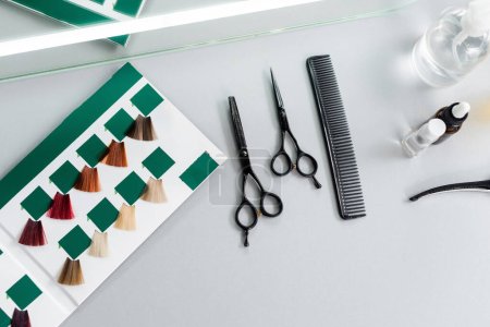 top view of hair cutting tools, hairdressing scissors, bottles, comb and hair palette book on white surface in beauty salon, hairdressing gear, beauty industry, hair fashion 