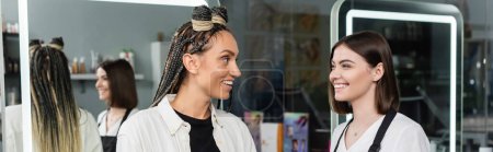 client satisfaction, hairdresser smiling with female customer, happy woman with braids, hairstyle, hair buns, braided hair, beauty salon, professional, mirror reflection, banner