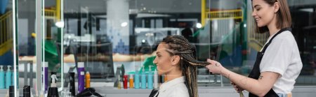 Photo for Side view, client satisfaction, hairdresser styling hair of female customer, looking at mirror, happy woman with braids, hairstyle, braided hair, beauty salon, hairstyling products, banner - Royalty Free Image