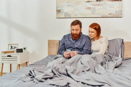 digital couple, screen time, networking, relaxing on weekends without kids, husband and wife, bearded man and redhead woman using smartphone, cozy bedroom, day off, tattooed couple, interior 