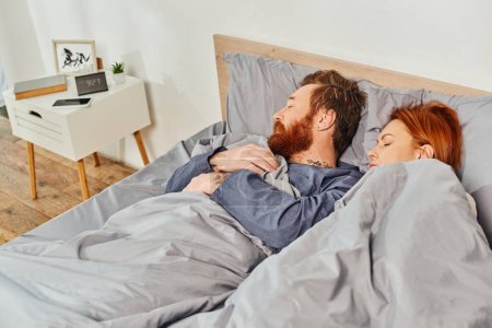 Photo for Parents alone at home, quiet house, redhead husband and wife sleeping in cozy bedroom, bearded man and carefree woman relaxing on weekends, day off, tattooed, closed eyes, interior - Royalty Free Image