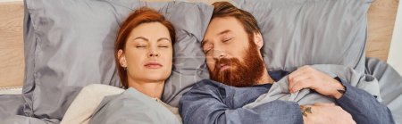 Photo for Quiet house, parents alone at home, redhead husband and wife sleeping in cozy bedroom, bearded man and carefree woman relaxing on weekends, day off, tattooed, closed eyes, banner - Royalty Free Image