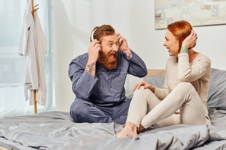 Photo for Happiness, excited and bearded man, day off without kids, redhead husband and wife, bearded man in wireless headphones, cheerful parents alone at home, modern lifestyle, listening music - Royalty Free Image