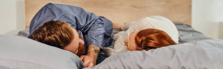 Photo for Day off without kids, tattooed people, couple relaxing together, lying on bed, redhead husband and wife, enjoying time together, bearded man and carefree woman looking at each other, banner - Royalty Free Image