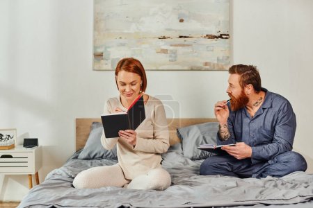 Photo for Writing experience, notebook romance, married couple taking notes, day off without kids, redhead husband and wife, enjoying time, day off, weekends together, tattooed, parents alone at home - Royalty Free Image