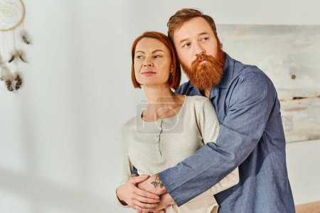 Photo for Married couple hugging in cozy bedroom, day off without kids, redhead husband and wife, enjoying time together, weekends together, tattooed, bonding, parents alone at home - Royalty Free Image