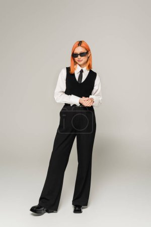 schwarze und weiße Kleidung, Business-Mode, asiatische Frau mit gefärbten Haaren posiert mit dunkler Sonnenbrille auf grauem Hintergrund, in voller Länge, Generation z, Business lässig, selbstbewusst und erfolgreich 