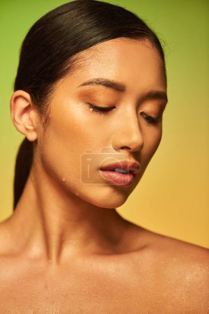 Wassertropfen im Gesicht, Nahaufnahme einer jungen asiatischen Frau mit feuchter Haut, die auf grünem Hintergrund posiert, geschlossene Augen, Hautfeuchtigkeit, Schönheitskampagne, Perfektion, Wohlbefinden, konzeptionelle 