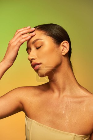 Hautfeuchtigkeit, junge asiatische Frau mit nackten Schultern und nassem Körper posiert auf Gradientenhintergrund, Stirn berühren, Hautpflege-Kampagne, Schönheitsmodel, brünettes Haar 