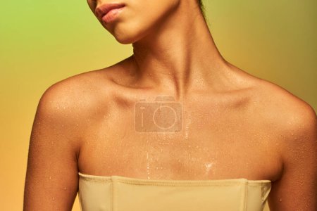Hydratation, abgeschnittene Ansicht einer jungen Frau mit nackten Schultern und nassem Körper posiert auf Gradientenhintergrund, Hautpflege-Kampagne, Schönheitsmodel, glühende Haut, grüner Hintergrund, natürliche Schönheit 