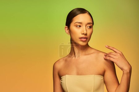 Schönheitskampagne, anmutige asiatische Frau mit nackten Schultern, junges Schönheitsmodel posiert auf grünem Hintergrund, Steigung, strahlende und jugendliche Haut, natürliche Schönheit, Hautperfektion 