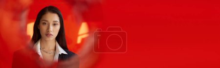 elegante atuendo, fotografía de moda, joven modelo asiático en camisa blanca y chaqueta posando en guantes cerca de vidrio redondo rojo, fondo gris, mirando a la cámara, estilo moderno, tendencia juvenil, bandera