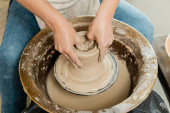 High angle view of young female potter in apron shaping wet clay while working on spinning pottery wheel in art workshop at background, skilled pottery making concept Sweatshirt #663415834