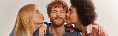 polygamy concept, open relationship, portrait of three adults, multicultural women kissing happy redhead man, polyamorous family in pajamas, cultural diversity, acceptance, banner 