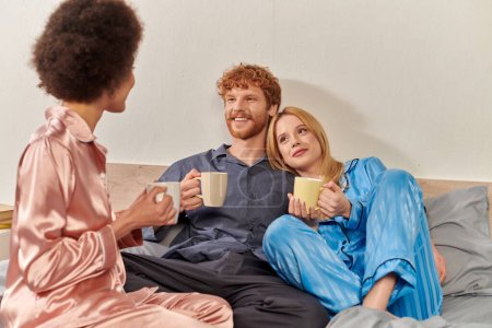 concept de relation ouverte, rousse homme et femmes interraciales en pyjama tenant tasses de café du matin, mode de vie, bisexuel, compréhension, trois adultes, diversité culturelle, acceptation 