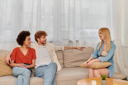 polygamy concept, acceptance, alternative relationships, african american woman sitting with redhead man and looking at blonde lover, cultural diversity, love triangle, freedom in relationship 