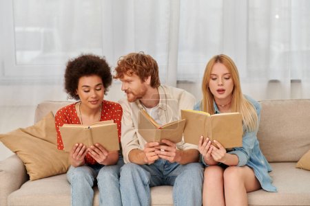relaciones alternativas, concepto de poligamia, mujeres multiculturales inteligentes leyendo libros con novio pelirrojo en la sala de estar, familia moderna, hobby y ocio, libertad en la relación 