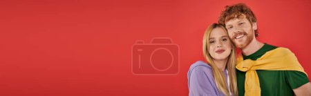 portrait of young couple looking at camera on coral background, vibrant colors, stylish outfits, modern family, husband and wife, bonding and love, togetherness, banner with copy space 