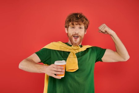 morning coffee, energy, showing muscle, redhead man with beard and curly hair holding paper cup on coral background, vibrant colors, male fashion, takeaway drink, male portrait, hot beverage 