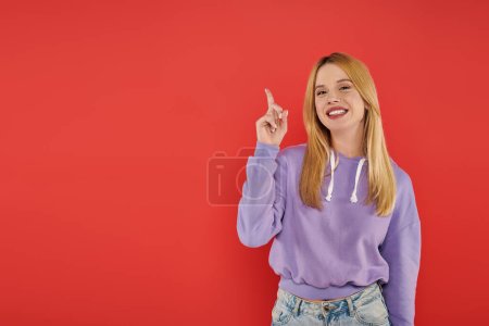 hand gesture, youthful fashion, blonde young woman in casual attire showing something on coral background, happiness, looking at camera, vibrant colors, fashion forward, modern individual, model 