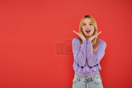 natural beauty, youthful fashion, amazed and blonde young woman in casual attire posing on coral background, happiness, looking at camera, vibrant colors, fashion forward, beautiful 