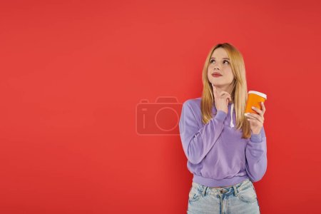 hot beverage, youthful fashion, blonde young woman in casual attire holding paper cup on coral background, happiness, looking away, vibrant colors, fashion forward, takeaway drink 
