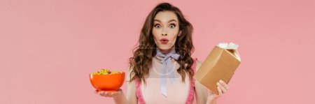 Photo for Housewife concept, shocked young woman posing like a doll, holding takeaway food and bowl with corn flakes, pink background, conceptual photography, home duties, emotional, banner - Royalty Free Image